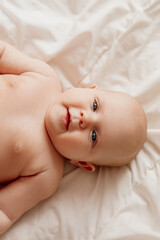 closeup portrait of a blue-eyed newborn baby lying on his back on a white sheet