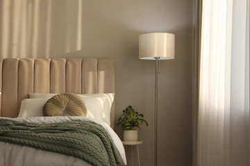 Stylish floor lamp and plant in bedroom. Interior element