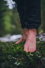 bare female feet on the grass with moss in the forest