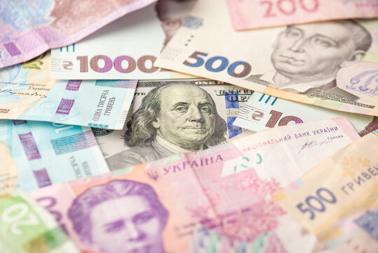 Photo of pile of ukrainian hryvnia banknotes and one hundred dollar banknote in the middle
