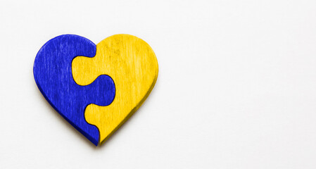 The wooden heart made like a puzzle in colors of Ukrainian flag
