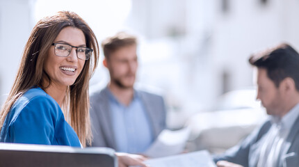 business woman sitting at a table on the background of colleagues