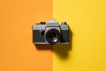 Retro analogue camera. Vintage old fashioned camera with lens on two colored background.