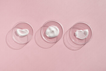 White cream textures in Petri dishes on a pink background. Concept of cosmetics laboratory researches. Smear of skincare cosmetics product. Wellness and beauty concept. Soft focus