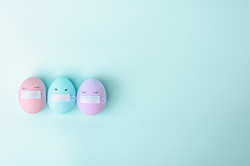 Three colorful Easter eggs with painted eyes and with protective mask covid-19. Happy Easter holidays. The concept of celebrating Easter on quarantine stay home