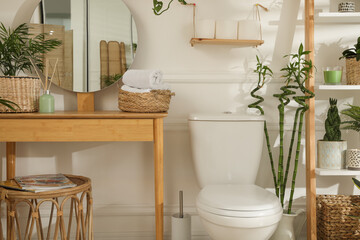 Stylish bathroom interior with toilet bowl and many beautiful houseplants