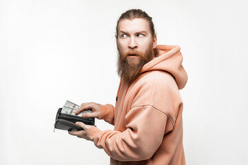 Handsom man holding paper currency in wallet and is unhappy on gray background. Hand pulling 100 dollars banknotes from wallet. Guy have cash. The concept of money, salary, finance, investment, save