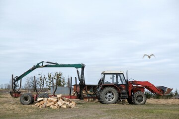 A tractor and a trailer with a crane for transporting timber in the countryside