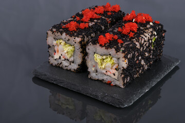 rolls with crab meat, red and black flying fish caviar on a black wooden tray