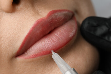 Young woman undergoing procedure of permanent lip makeup in salon, closeup - obrazy, fototapety, plakaty