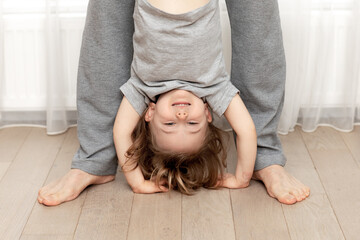 dad holds upside down fun smiling adorable child Natural trend calm colores grey clothers and beige...