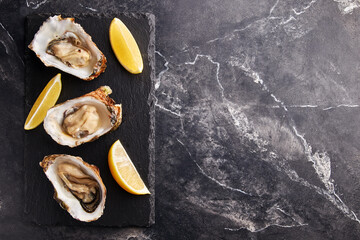 Fresh opened oyster with lemon on slate plate - 496061800