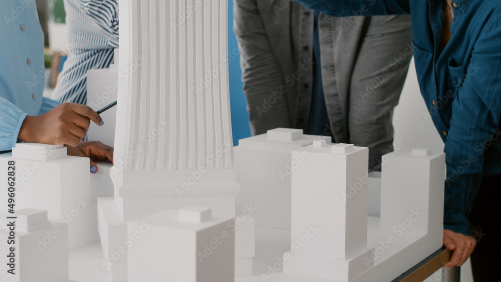 Poster close up of team of people analyzing building model on table to plan urban construction. diverse col