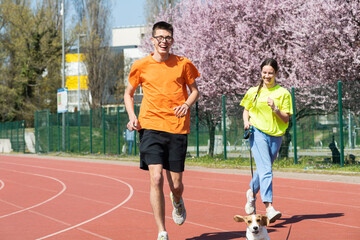 Young happy couple running with a dog