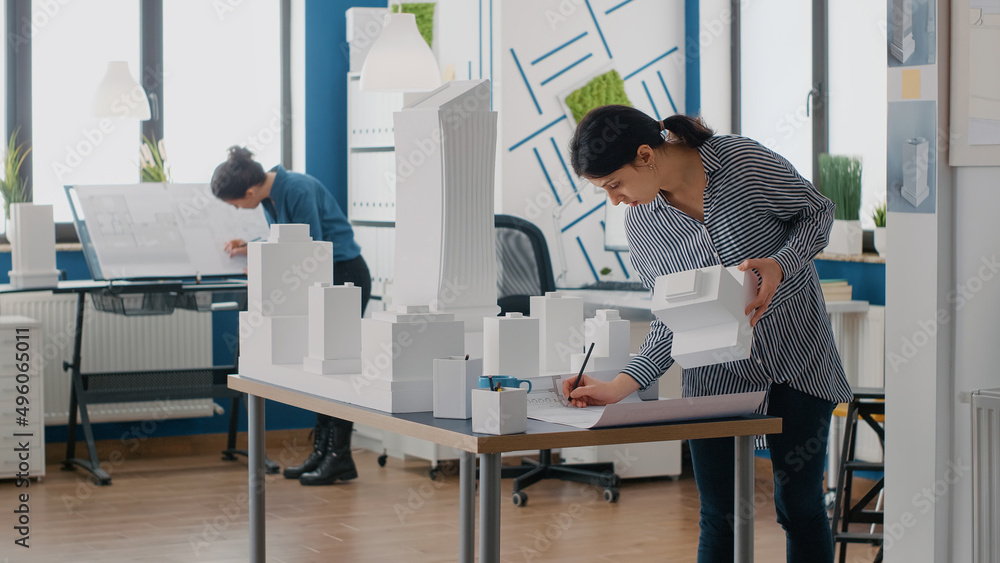 Aufkleber contractor holding building model to design blueprints plans on table. expert architect working with