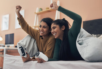 They didnt stand a chance against these sisters. Shot of two young women playing video games at...