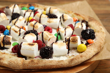 Tasty sweet pizza with berries, marshmallows and candies on table, closeup