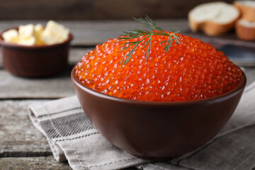 Bowl with delicious red caviar and dill on wooden table