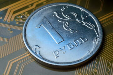 A coin with a face value of 1 ruble lies on a microcircuit. close-up. Translation of the inscription on the coin: "1 ruble" The concept of the digital economy in the Russian Federation