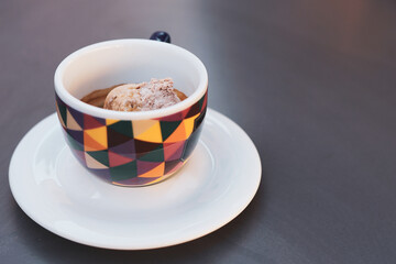 Closeup of a cup of coffee with a scoop of ice cream inside. Affogato al caffè, a typical way of drinking coffee in Italy. Ice cream with coffee in a colorful cup. Summer and snack time.