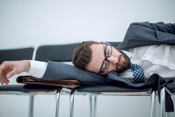 Fototapeta premium tired businessman sleeping on chairs in the office hallway