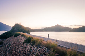 Man walking alone the dam, evening of Plover Cove Reservoir, Hong Kong