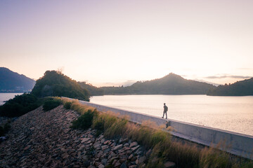 Man walking alone the dam, evening of Plover Cove Reservoir, Hong Kong