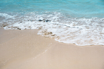 Fototapeta na wymiar Soft blue oceans wave with foam and clear white sand. Tropical beach by the ocean 