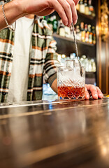 man hand bartender making glass negroni cocktail in bar