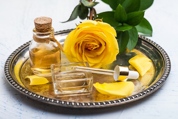 yellow rose flower and  bottle essential oil or rose water with rose petals
