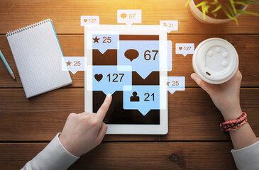 social media, technology and people concept - close up of female hands with virtual icons over tablet pc computer, notebook and coffee on wooden table