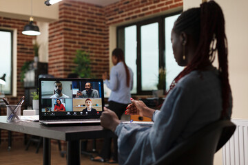 Fototapeta na wymiar African american company team leader in video call digital conference with executive board. Businesswoman discussing through videocall with coworkers about marketing strategy of startup project.