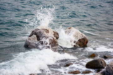 Dead Sea. Jordan. Close-up. Salt crystals on huge boulders along the coast. Close-up. Stone beaches along coast of Dead Sea are washed by foamy emerald waters.