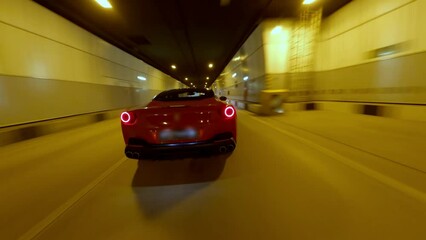 Speed flight follow movement FPV drone aerial view dark tunnel with fast driving red sport car. Dangerous riding automobile vehicle blurred lights urban travel transportation underground highway