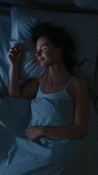 Top View of Beautiful Young Woman Sleeping Cozily on a Bed in His Bedroom at Night. Vertical Screen Orientation Video