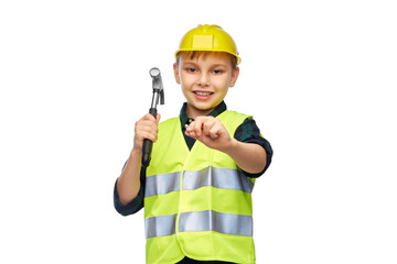 building, construction and profession concept - happy smiling little boy in protective helmet and safety vest with hammer nailing nail over white background