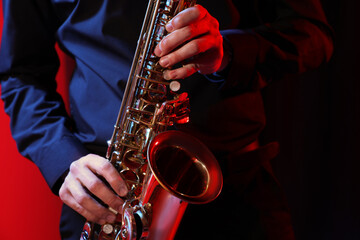 Man with saxophone on dark background, closeup