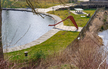 Natural swimming pool with a view from above to the swimming pond with a slide from above