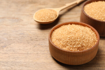 Different dishes with brown sugar on wooden table, closeup. Space for text