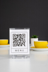 QR code for online menu service at table in restaurant New contactless technology lifestyle protect. Yellow mugs on a white table.