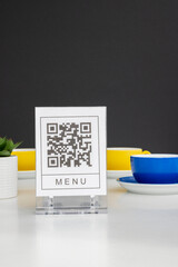 QR code for online menu service at table in restaurant New contactless technology lifestyle protect. Yellow and blue mugs on a white table