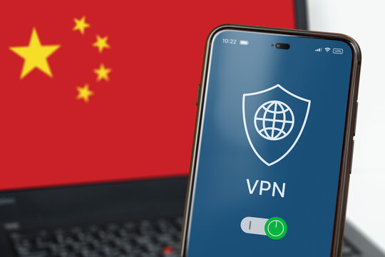 VPN in China. A smartphone with VPN turned on in the foreground and a laptop screen with a China flag in the background. Using VPN on cell phone and computer. Selected focus