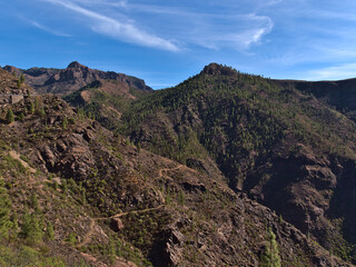 Beautiful view of the rugged mountains near road GC-605 in the center of island Gran Canaria, Spain with hiking path and pine trees on the slopes.