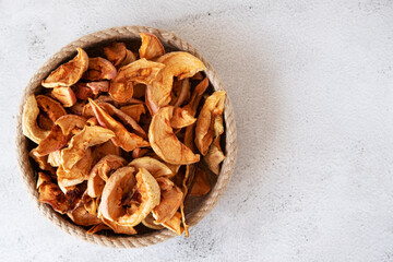Dried raw apples in a basket made of jute thread on a light background with room for text