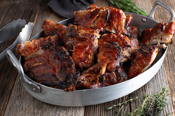 Barbecue ribs in a roasting pan on wooden table