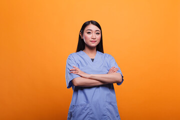 Confident and happy asian hospital staff worker with hands in pockets, wearing clinic related...
