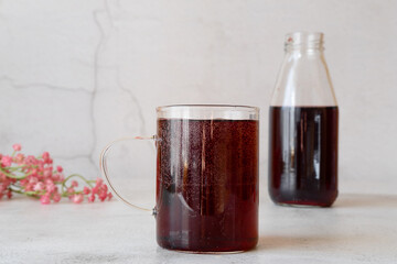 A glass glass with fresh pomegranate juice with mineral water and a bottle of juice in the background.
