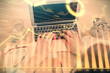 Double exposure of man's hands typing over laptop keyboard and forex chart hologram drawing. Top view. Financial markets concept.