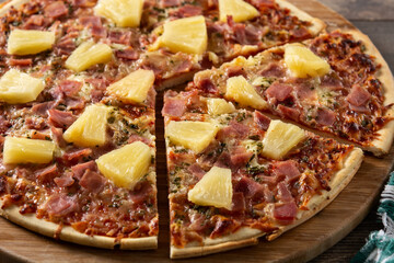 Hawaiian pizza with pineapple,ham and cheese on wooden table	