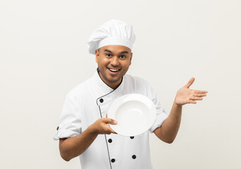 Attractive Young handsome asian man chef in uniform holding empty plate delicious dish menu good taste on isolated. Cooking indian man Occupation chef or baker People in kitchen restaurant and hotel.